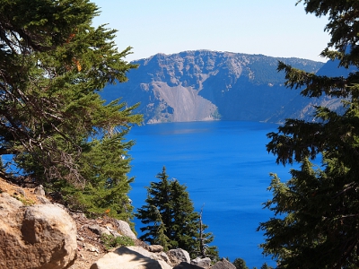 [Framed between evergreens on the left and right is a view of the lake with the crater's edge in the distance.]